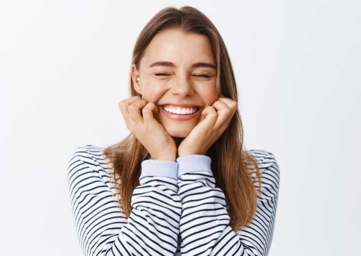 Chica joven sonriendo pensando: ¿Brackets o Invisalign? Ortodoncia en Cuenca