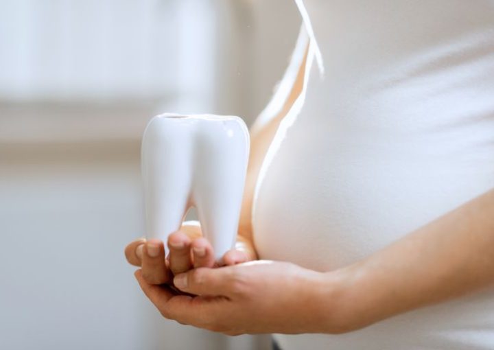 Mujer posa con diente preocupada por su salud bucodental y el embarazo - Dentista en Cuenca - Millán